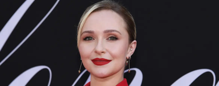 Hayden Panettiere in a red suit jacket and dangling earrings posing against a black backdrop with white text. Hayden Panettiere in a red suit jacket and dangling earrings posing against a black backdrop with white text.