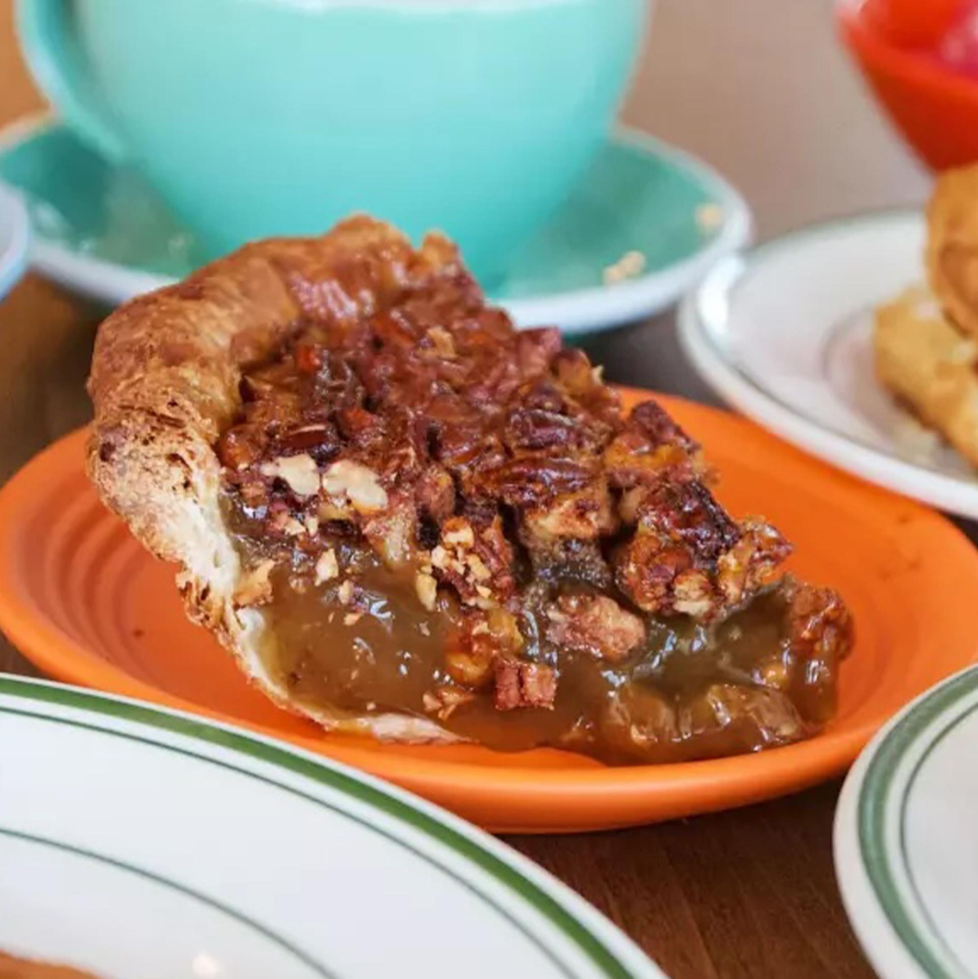 A side photo of an array of dishes from Fat and Flour Culver City. At center is a slice of pecan pie.