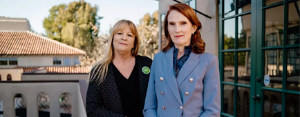 Two women pose next to a railing. Two women pose next to a railing.