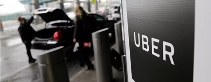 A person opens the trunk of a car near a sign that says "Uber."