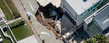 A sinkhole is seen from a drone on a street and driveway of a seaside home