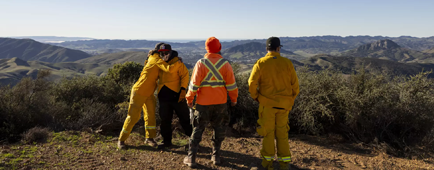 Members of the yak titʸu titʸu yak tilhini Northern Chumash Tribe in firefighting gear looking out at open space Members of the yak titʸu titʸu yak tilhini Northern Chumash Tribe in firefighting gear looking out at open space