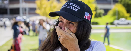 A woman wearing a Make America Great Again hat cries. 