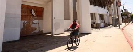 A bicyclist rides past the boarded-up main entrance of the Hawthorne Plaza mall on Aug. 21.