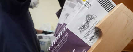 A worker sorts mail ballots. A worker sorts mail ballots.