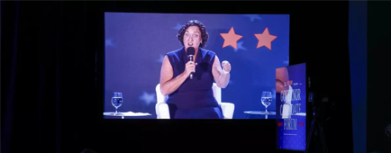 Gubernatorial candidate Katie Porter, shown on screen speaking to a crowded room