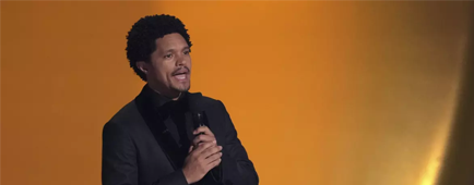 Trevor Noah speaks into a microphone on stage.