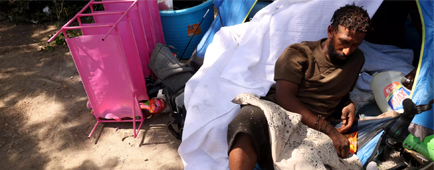 A man lies on the ground outside a tent.