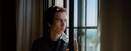 A young man sits near the window of a hotel.