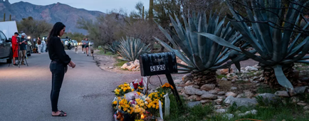 Flowers are left by a mailbox outside a home.