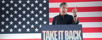 Gov. Gavin Newsom speaks at a lectern with a placard reading