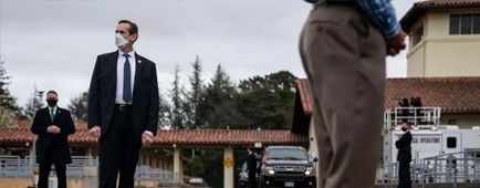 Secret Service agents stand in a parking lot.