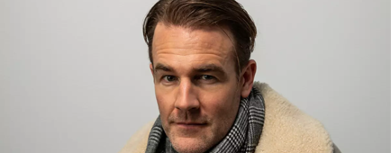 James Van Der Beek wearing a coat and scarf sits with his hands clasped on a table