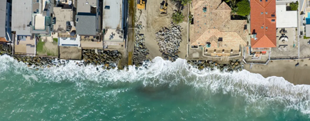 Crews work along the shoreline as coastal erosion and damage threaten beachfront homes.