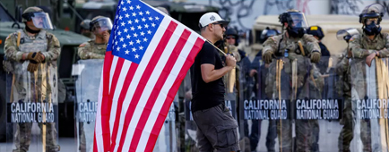 A demonstrtor walks with an American flag.
