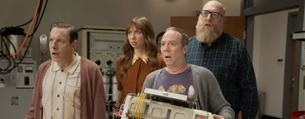 Three men and a woman standing with surprised looks on their faces.