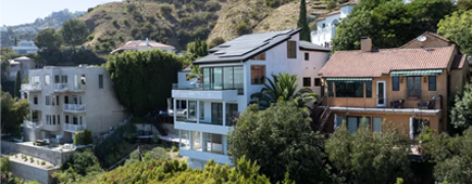 Three multistory homes on a hillside, two of them white, and one in brown Three multistory homes on a hillside, two of them white, and one in brown